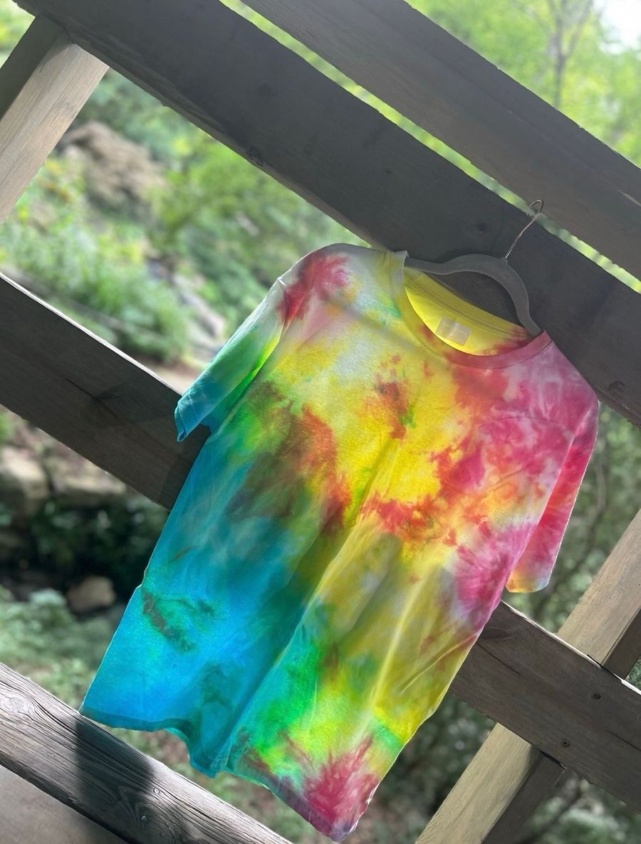 A rainbow ice-dyed tee drying outdoors